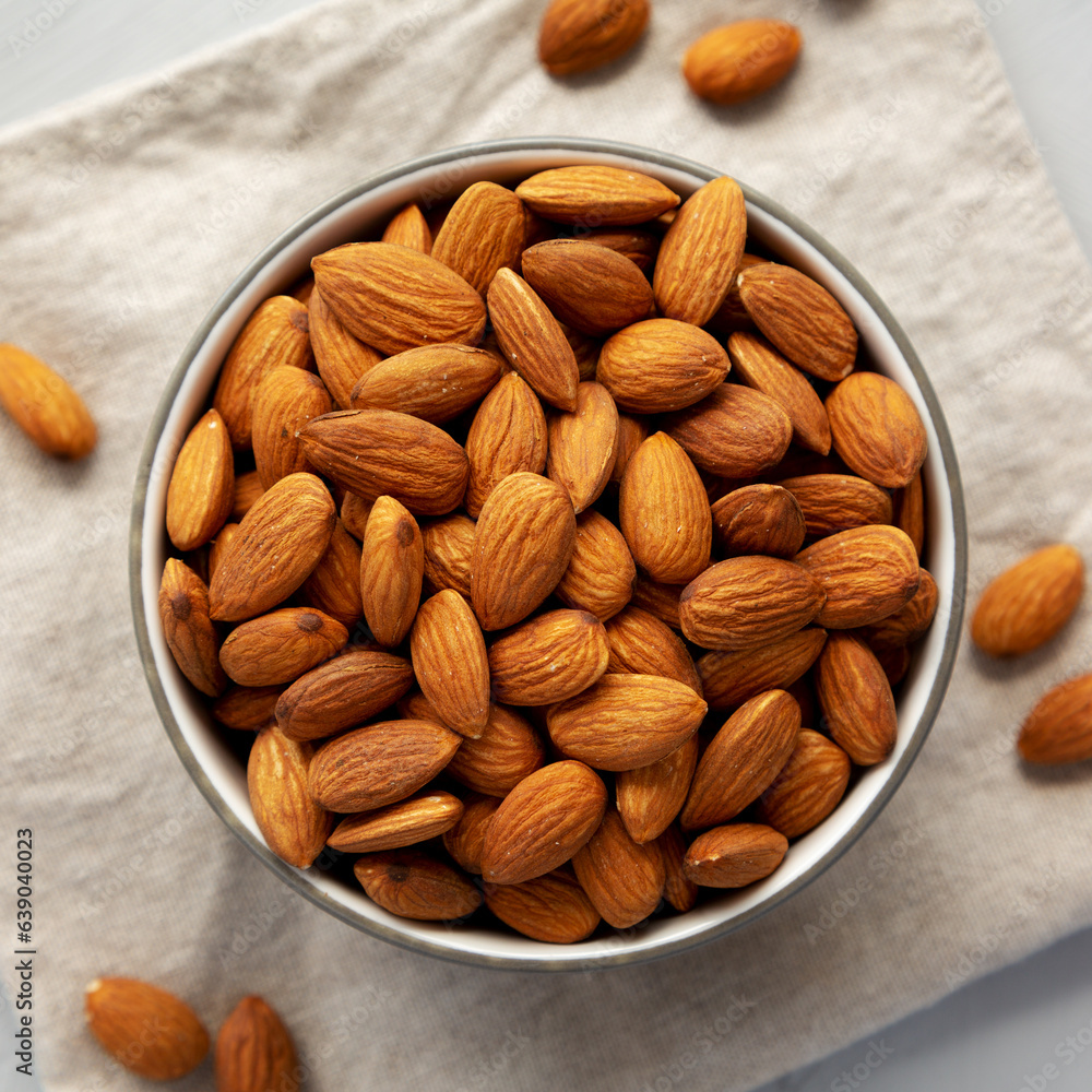 Raw Organic Almonds in a Bowl on a gray background, top view. Raw Organic Almonds in a Bowl on a gray background, top view.