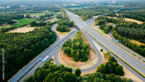 Aerial view of German highway autobahn . Drone shot of highway among forest and green field. Cars fast speed moving on freeway.