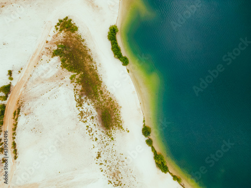 Aerial drone top down view of lake with sandy shore and turquoise water in summer day. 