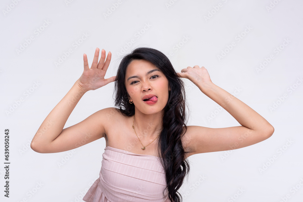 A young asian woman sticking her tongue out waving one's hands on either side of one's face, taunting or teasing a friend or enemy. Isolated on a white background. A young asian woman sticking her tongue out waving one's hands on either side of one's face, taunting or teasing a friend or enemy. Isolated on a white background.
