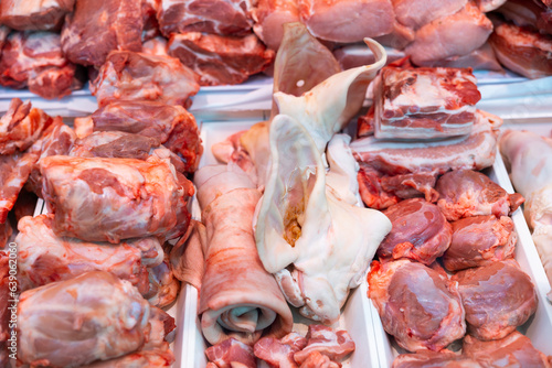 Closeup of fresh raw pork meat, bacon, ears and lard offered for sale in showcase. Large assortment of butchery produce