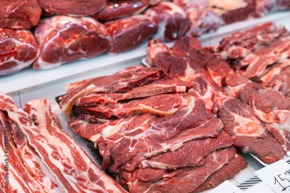 Closeup of fresh raw veal chops, tenderloin, short ribs and steaks offered for sale in showcase. Large assortment of butchery produce