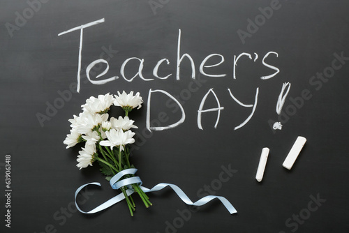 Beautiful flowers with chalks and text TEACHER'S DAY on blackboard