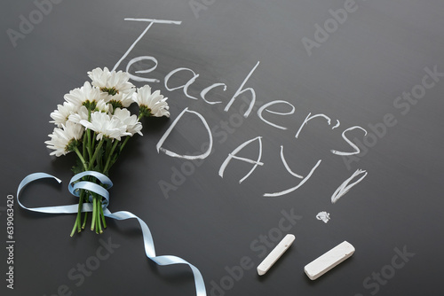 Beautiful flowers with chalks and text TEACHER'S DAY on blackboard