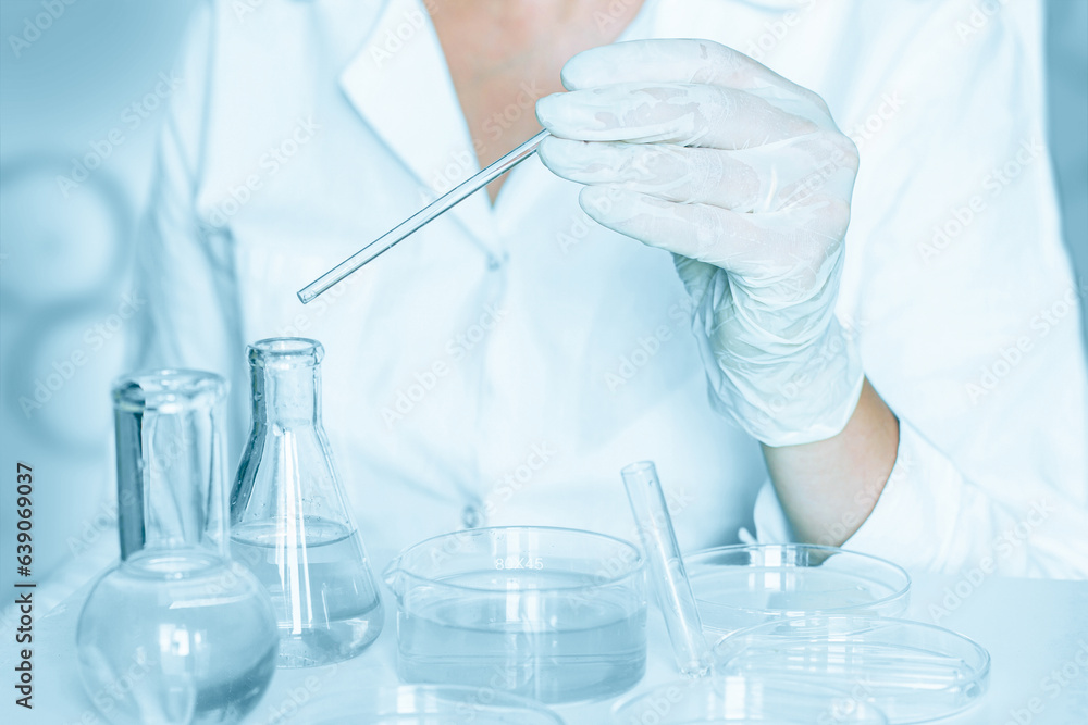 In the laboratory: Aide carefully performs actions in the laboratory surroundings. Wearing a lab coat. Utilizing glass instruments. Blue laboratory context. In the laboratory: Aide carefully performs actions in the laboratory surroundings. Wearing a lab coat. Utilizing glass instruments. Blue laboratory context.