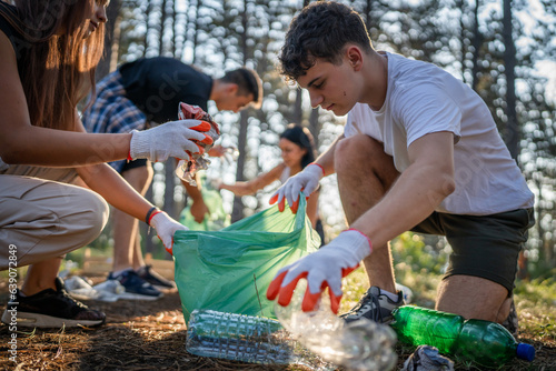 Bild auf Leinwand teenage friends young men women pick up waste garbage to clean forest