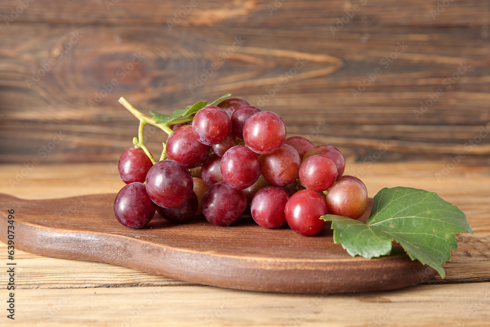 Board with tasty ripe grapes on wooden background Board with tasty ripe grapes on wooden background