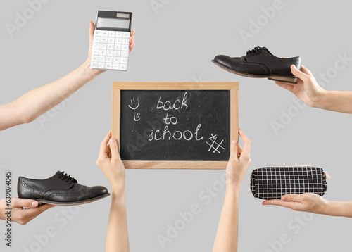 Female hands holding stationery, school shoes and blackboard with text BACK TO SCHOOL on grey background photo