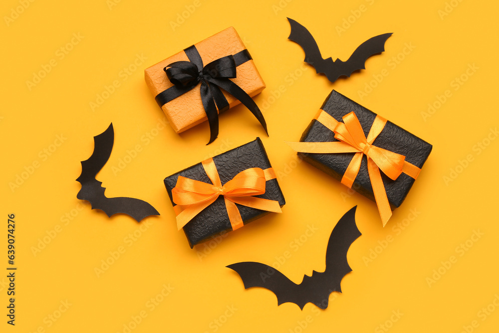 Fototapeta premium Paper bats for Halloween party and gift boxes on orange background