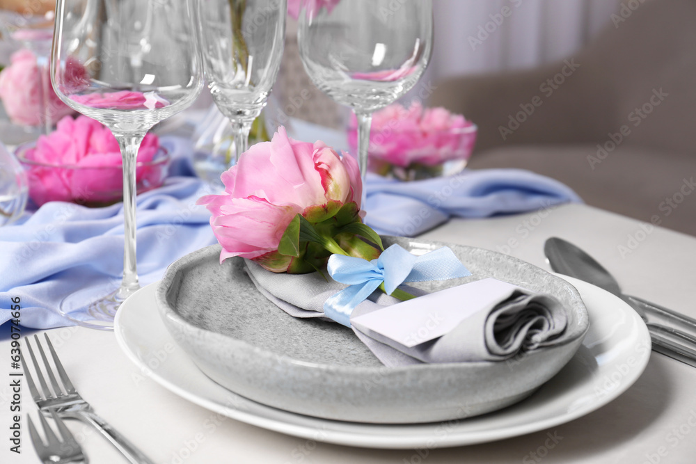 Stylish table setting with beautiful peonies, napkin and blank card indoors, closeup Stylish table setting with beautiful peonies, napkin and blank card indoors, closeup