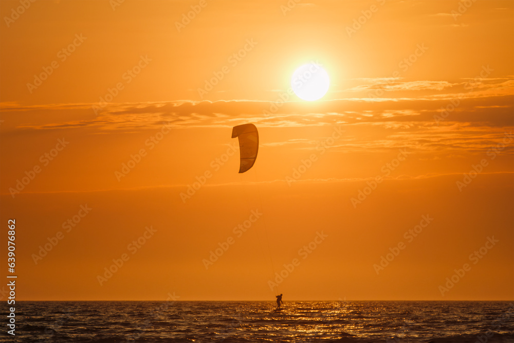 Foiling kiteboarding kitesurfing kiteboarder (kitesurfer) silhouette in the Atlantic ocean on sunset. Fonte da Telha beach, Costa da Caparica, Portugal Foiling kiteboarding kitesurfing kiteboarder (kitesurfer) silhouette in the Atlantic ocean on sunset. Fonte da Telha beach, Costa da Caparica, Portugal