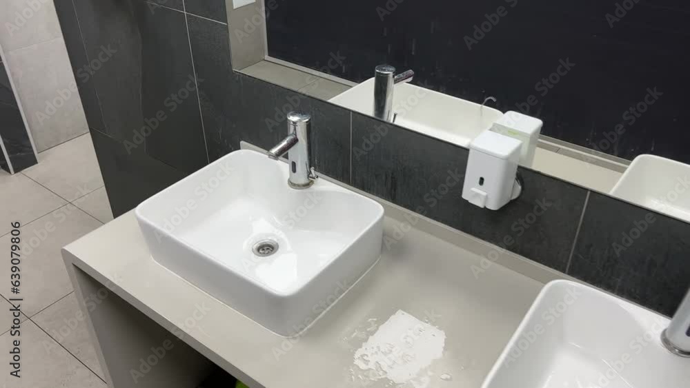 Modern square washbasins lined up in a public restroom Modern square washbasins lined up in a public restroom