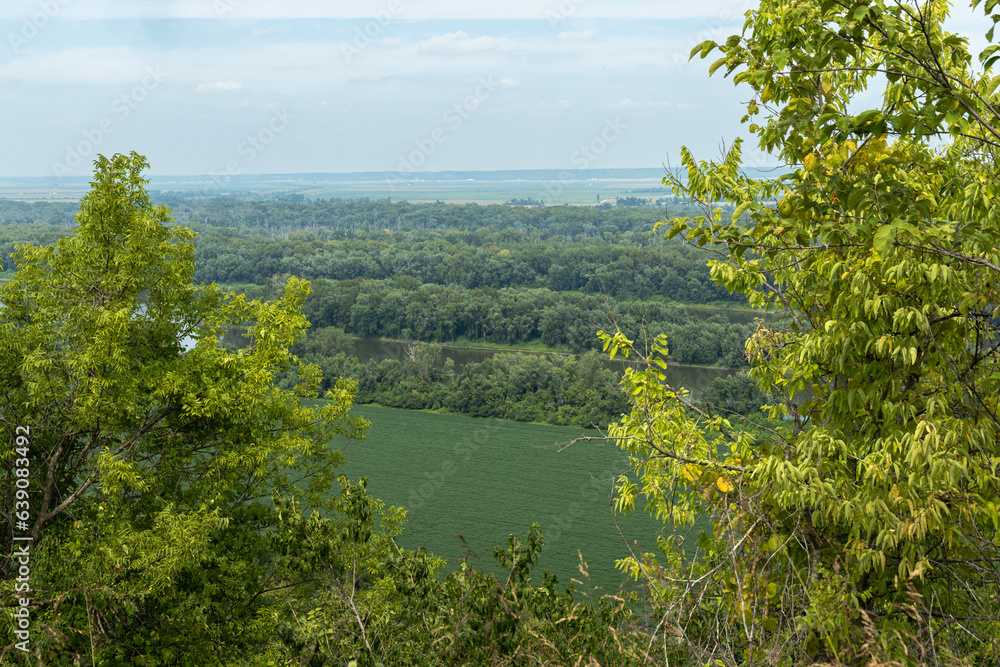 Mississippi river from the top of a hill on a hazy day with farm fields in the foreground and trees on either side