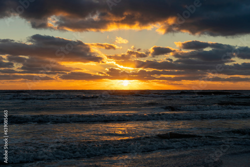 Evening landscape of sea water waves crushing on sandy beach at sunset © bilanol