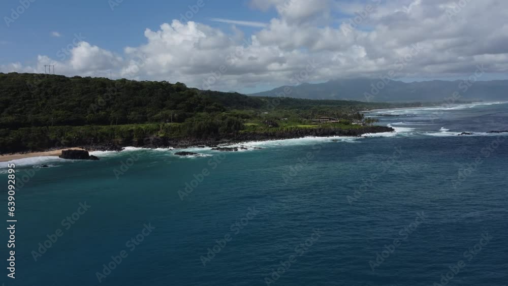Aerial view of waves hitting the beach in Oahu, Hawaii with mountains at distance Aerial view of waves hitting the beach in Oahu, Hawaii with mountains at distance