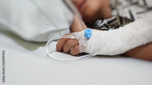Blurry image of a sick boy sleeping in a hospital bed with an IV in hand
