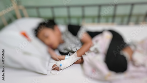 Blurry image of a sick boy sleeping in a hospital bed with an IV in hand