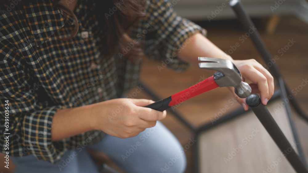 Women using hammer equipment to assembling and repairing chair while making furniture for new house
