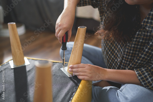 Women tighten screw with screwdriver equipment for repairing leg of chair and assembling furniture