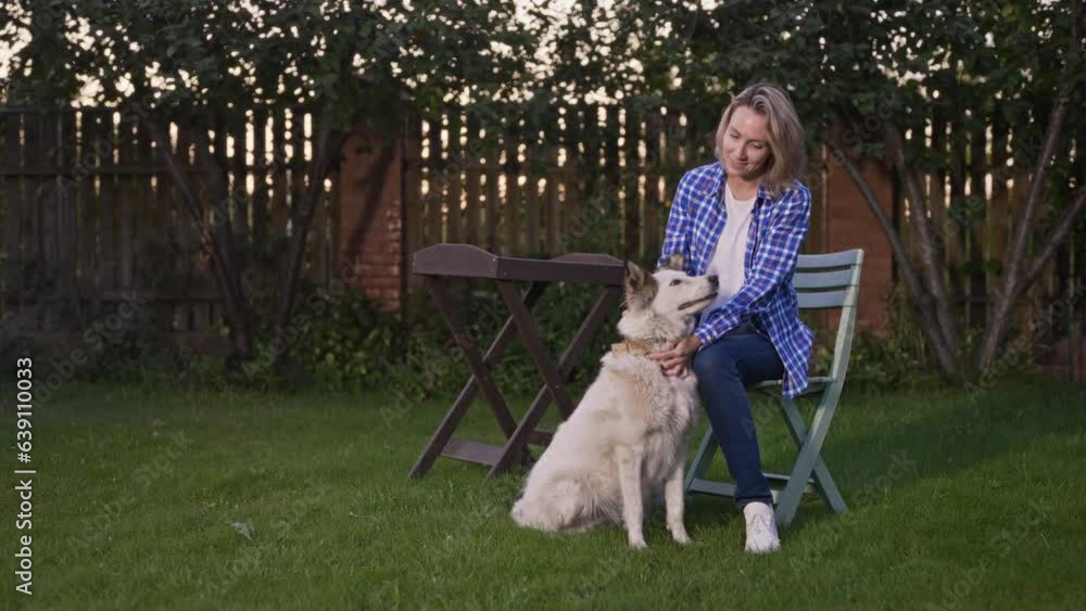 Hostess with her dog in a country garden. A woman is resting after work and spending time outdoors with her pet.