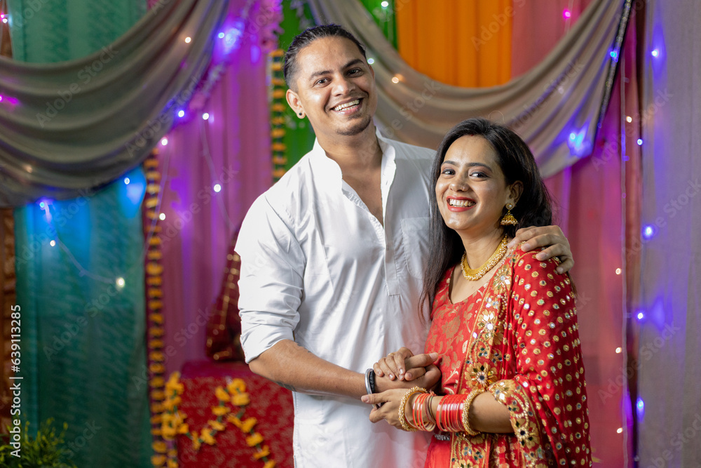 Indian couple in ethnic wear on the occasion of Diwali looking towards the camera , Happy couple celebrating diwali at home