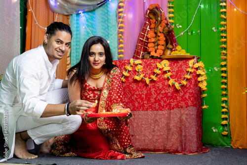 Indian couple decorating home with diya and looking towards the camera ,Festival occasion celebration at home © Photographielove