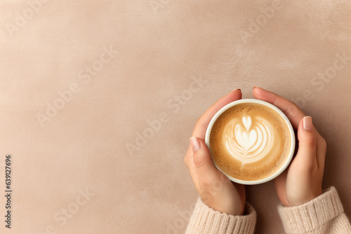 Leinwand Poster close up of woman in a cosy warm sweater holding a cup of coffee with latte art
