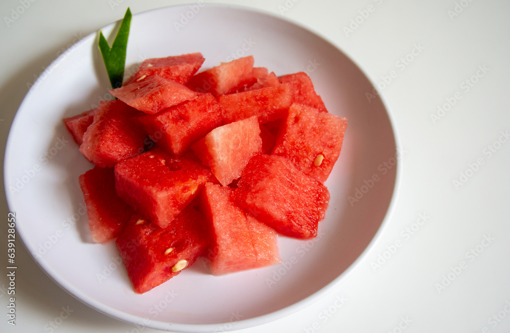 Freshly sliced watermelon on a white plate with a wood pattern background Freshly sliced watermelon on a white plate with a wood pattern background