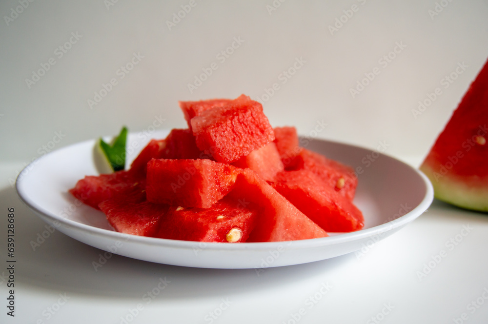 Freshly sliced watermelon on a white plate with a wood pattern background Freshly sliced watermelon on a white plate with a wood pattern background