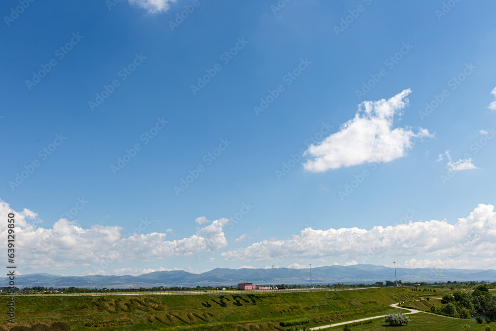 Landscape with grass field, blue sky and clouds