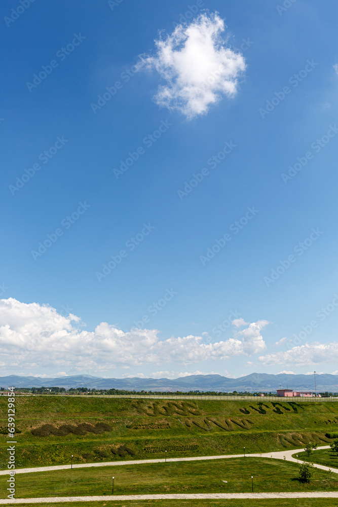 Landscape with grass field, blue sky and clouds