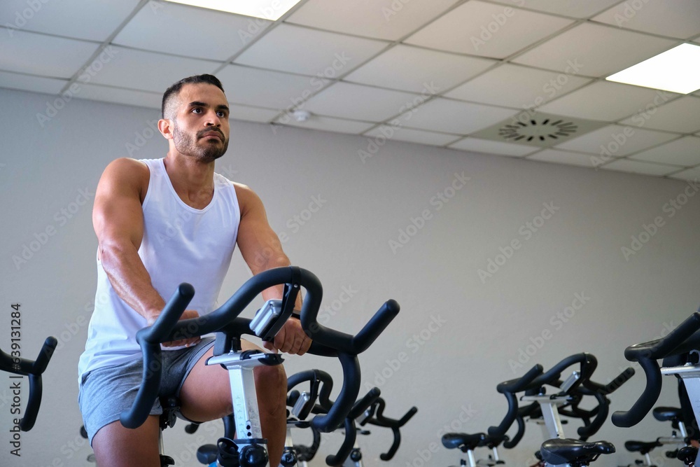 Strong Hispanic man doing spinning cycling at a gym. Strong Hispanic man doing spinning cycling at a gym.