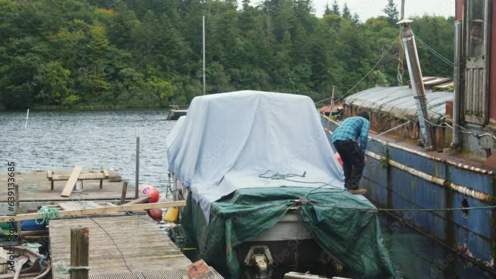 A man mooring a wooden boat with covers to a dock. Timelapse A man mooring a wooden boat with covers to a dock. Timelapse
