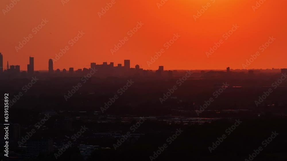 Sun rising with dramatic bright orange skyline over Rotterdam below, pan left Sun rising with dramatic bright orange skyline over Rotterdam below, pan left