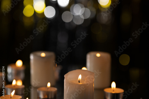 Lit tea candles and candles with copy space on black background