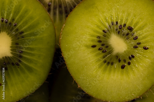 Micro close up of sliced kiwi fruits with water drops and copy space on black background