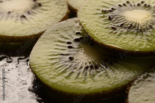 Micro close up of sliced kiwi fruits with water drops and copy space on black background