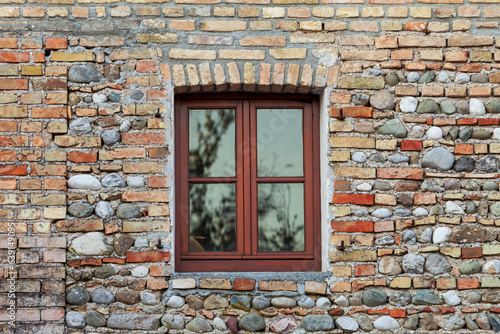 Vecchio muro di mattoni con una finestra e blocchi di pietra. Sfondo astratto.