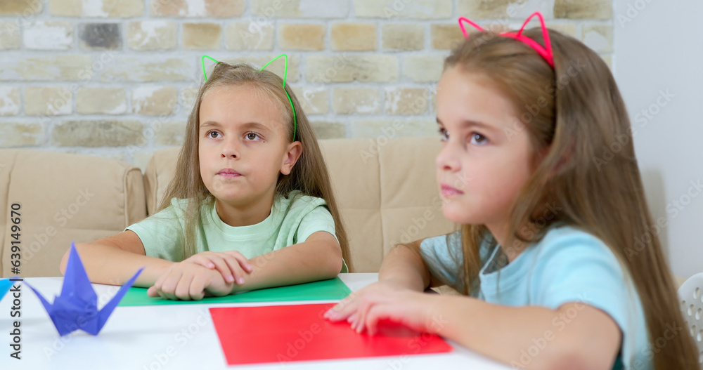 School children on vacation sit on the couch and fold origami School children on vacation sit on the couch and fold origami
