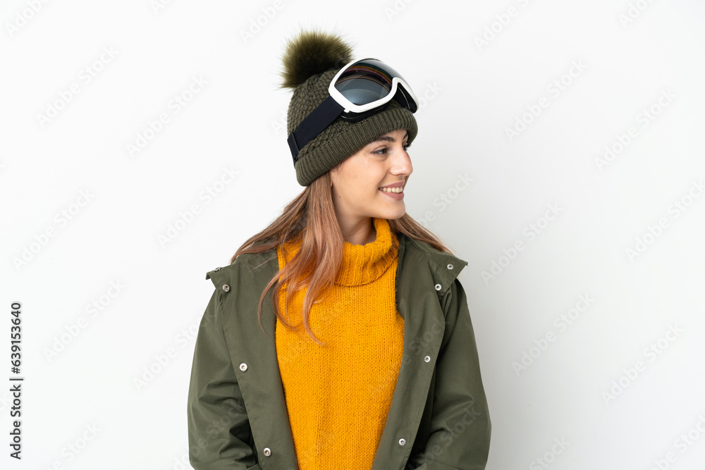 Skier caucasian woman with snowboarding glasses isolated on white background looking to the side and smiling