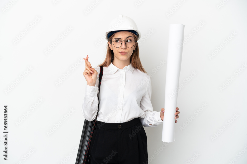 Young architect woman with helmet and holding blueprints isolated on white background with fingers crossing and wishing the best Young architect woman with helmet and holding blueprints isolated on white background with fingers crossing and wishing the best