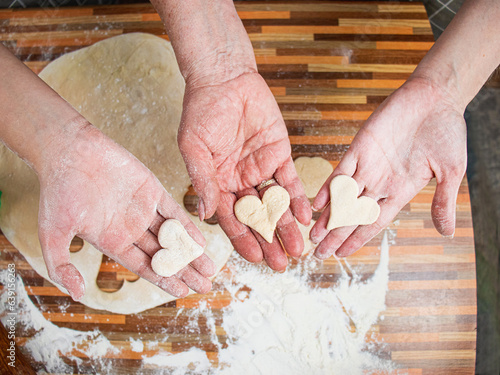 hands of grandmother, mother and granddaughter holding heart-shaped dough, three generations concept, heart-shaped cookies, family hearth, family cooking together, heart shaped cookies,