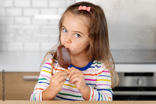 Young girl eating ice cream at kitchen table