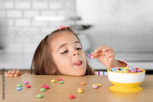 Young girl grabbing candy on kitchen table photo