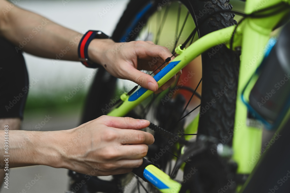 Asian male cyclist fixing his bicycle in the park in the summer day. Sport, emotions and healthy lifestyle