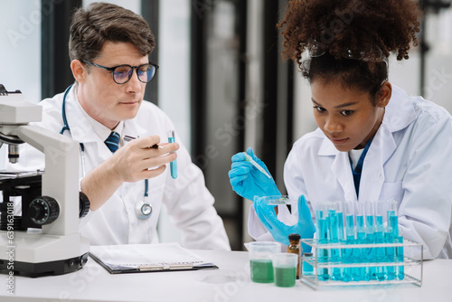 Medical Research Laboratory: Two scientists working, using microscope, analyzing samples, talking, developing biotechnology.