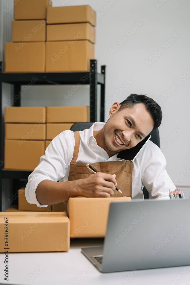 young man start up small business owner writing address on cardboard box at workplace.small business entrepreneur SME or freelance, man working with box at home. young man start up small business owner writing address on cardboard box at workplace.small business entrepreneur SME or freelance, man working with box at home.
