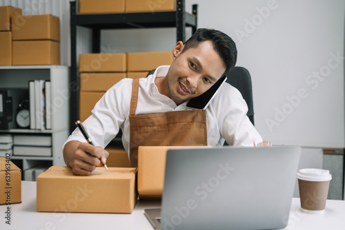young man start up small business owner writing address on cardboard box at workplace.small business entrepreneur SME or freelance, man working with box at home.