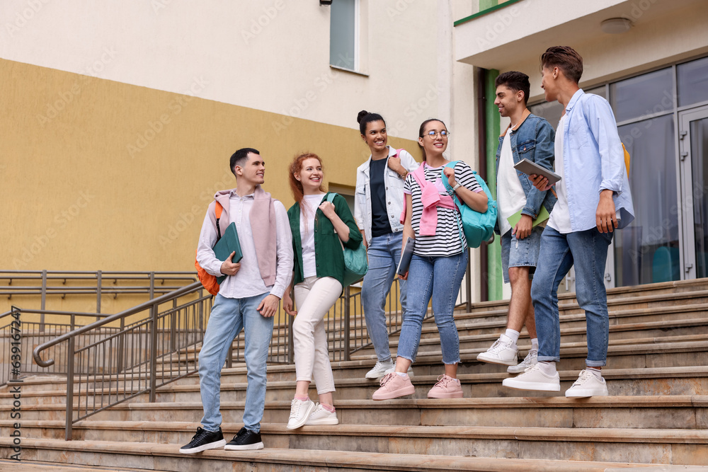 Obraz premium Group of happy young students walking down stairs outdoors