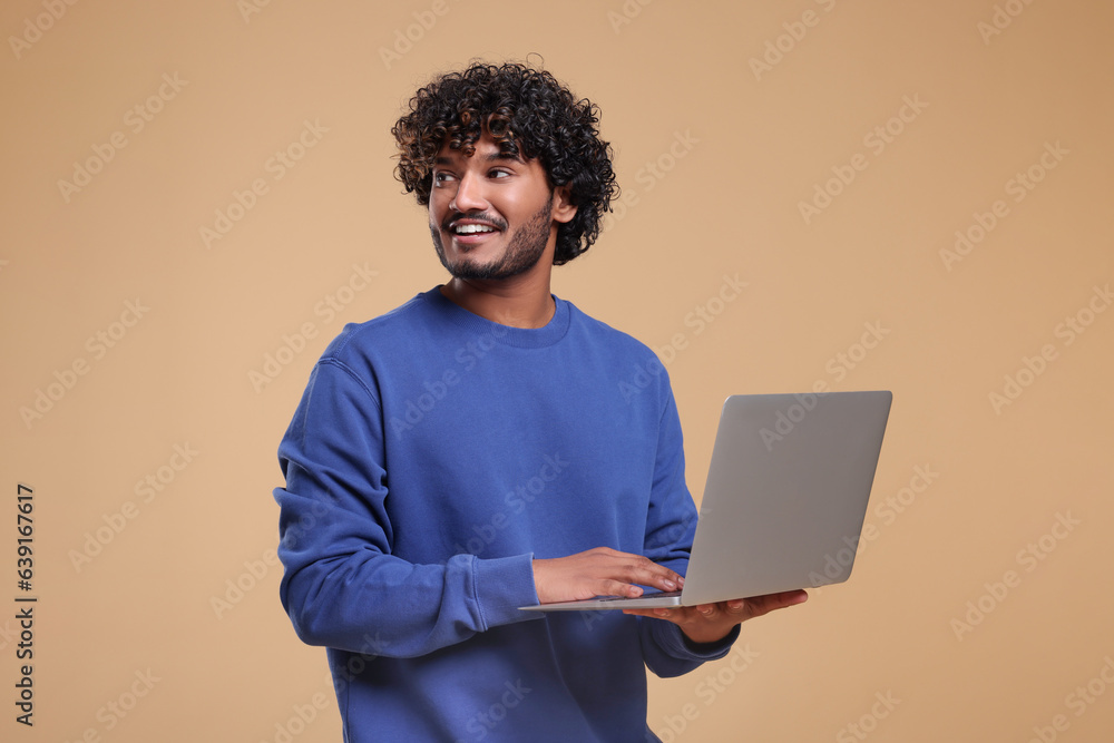 Smiling man with laptop on beige background Smiling man with laptop on beige background